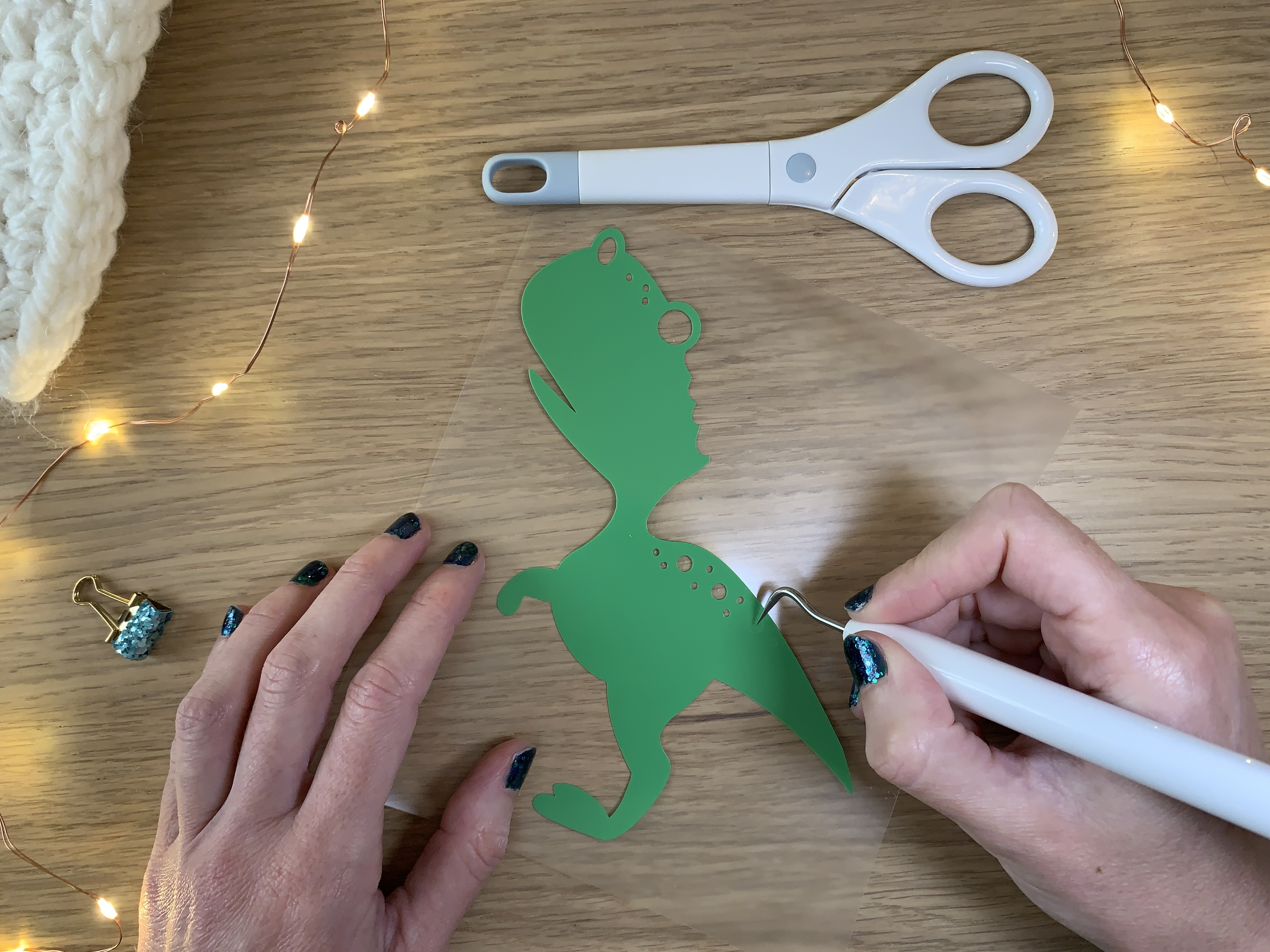 Échenillage du flex thermocollant multicolore après la découpe du motif dinosaure Noël