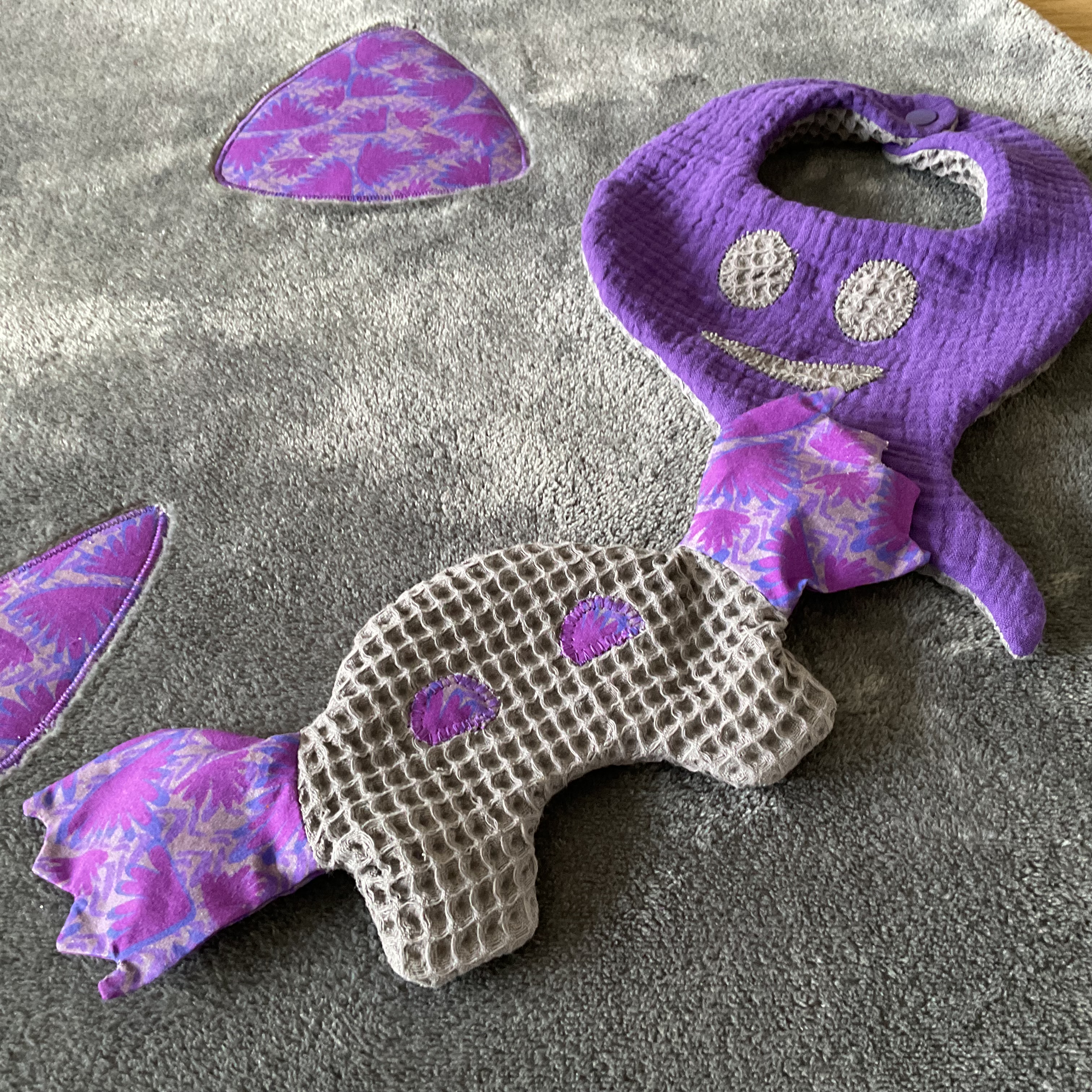 Zoom sur l’ensemble bébé Halloween : bavoir fantôme, couverture citrouille et doudou chauve-souris en tissus gris et mauve