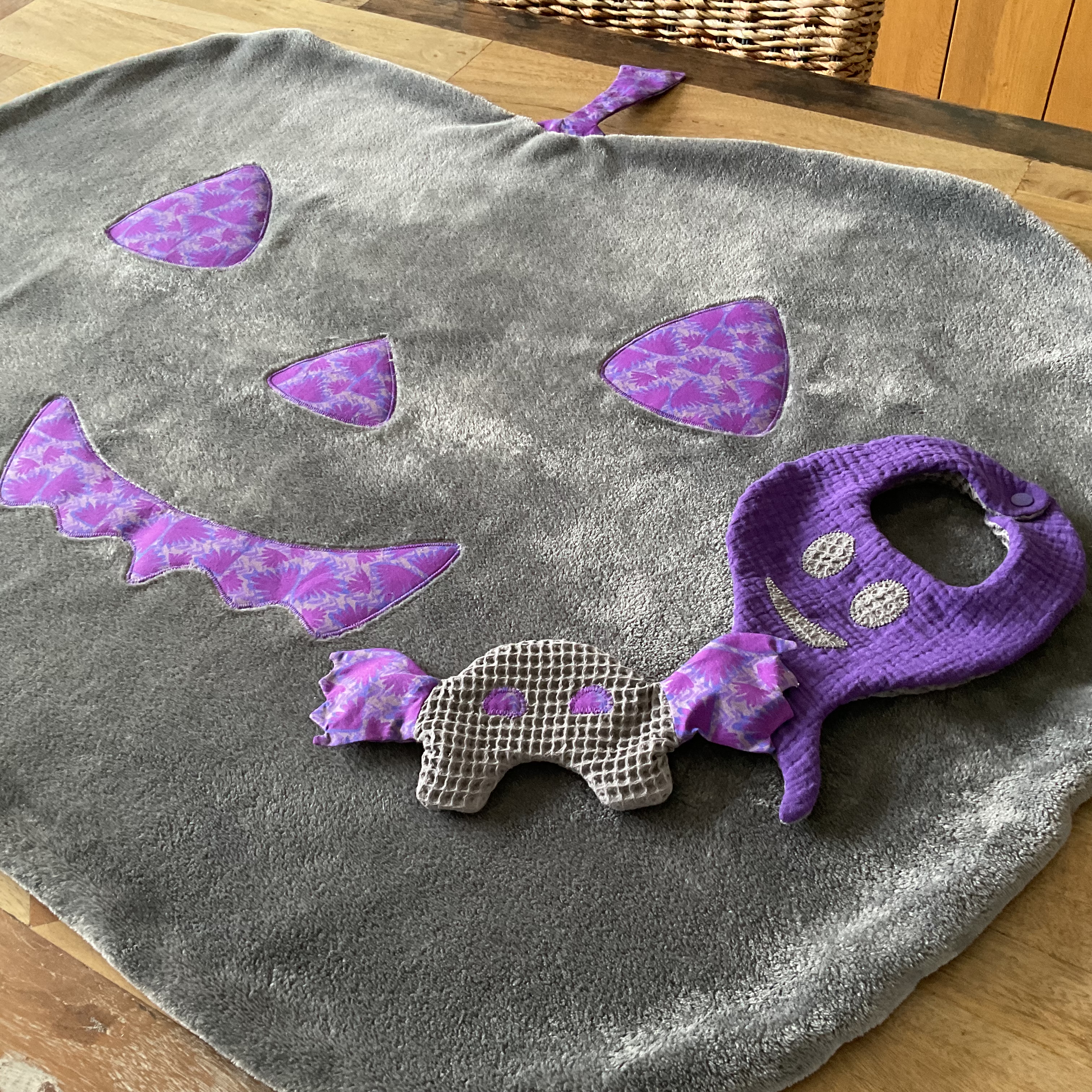 Vue d’ensemble de biais du kit bébé Halloween : bavoir, couverture et doudou en tissus automnaux gris et mauve