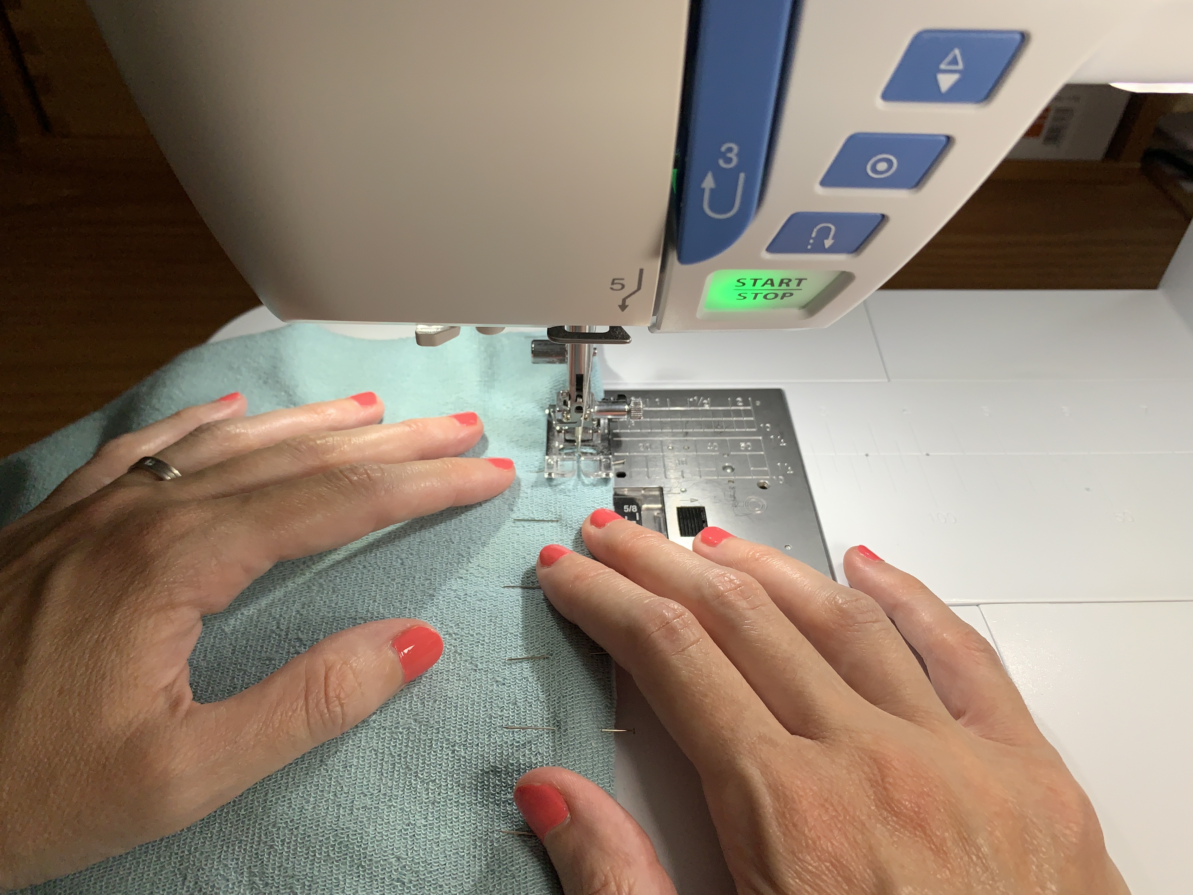Piquer à la machine à coudre les deux pièces de tissu rayé épinglées ensemble lentement
