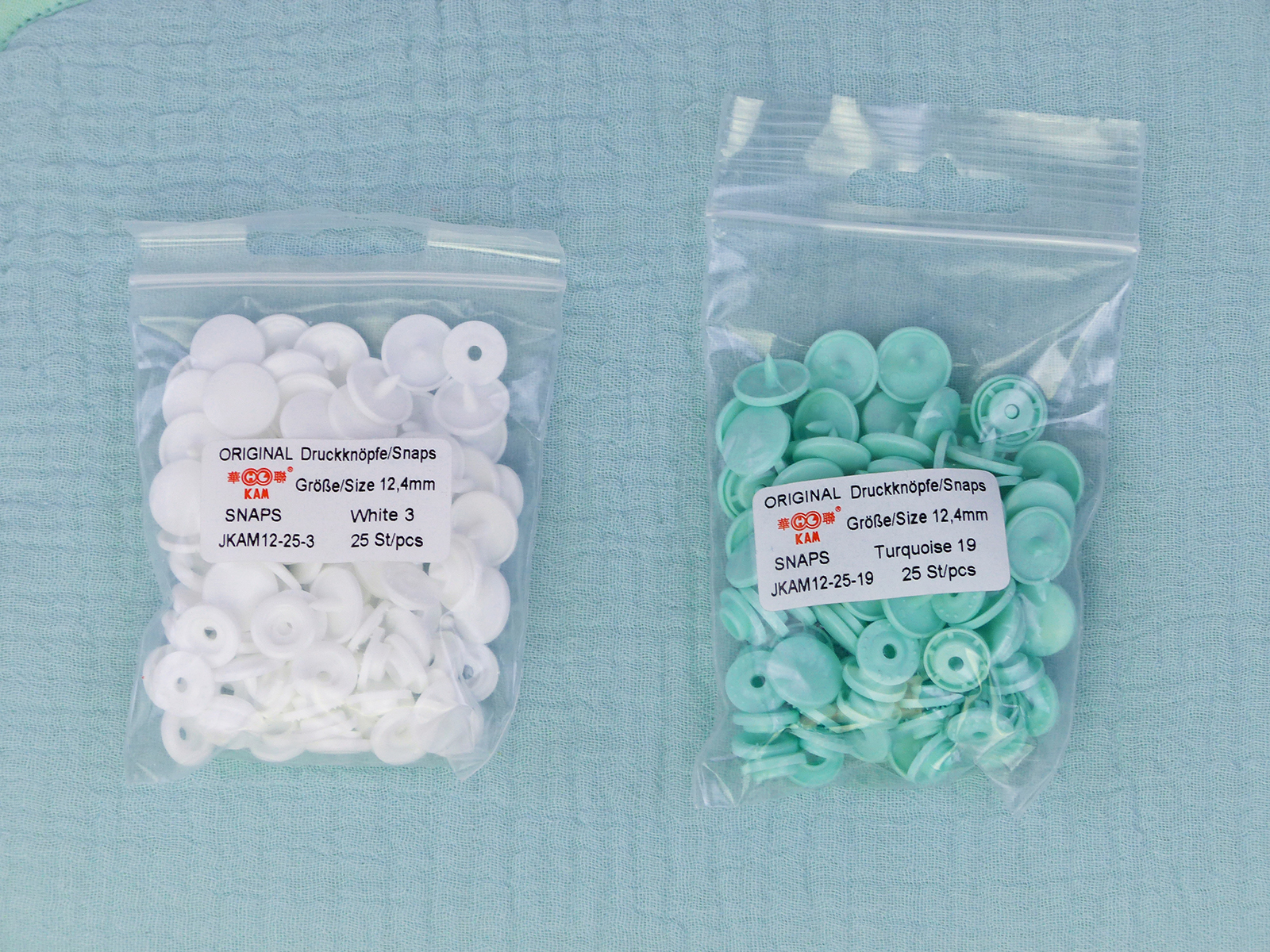 Deux coloris de pressions Kam en résine utilisés au quotidien pour bavoirs et accessoires bébé